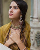 Model wearing the Aurus Jewels Aesha Necklace - a gold necklace with emerald and diamond motifs, pearl strands, and ruby drop fringe, styled as a layered statement neckpiece.
