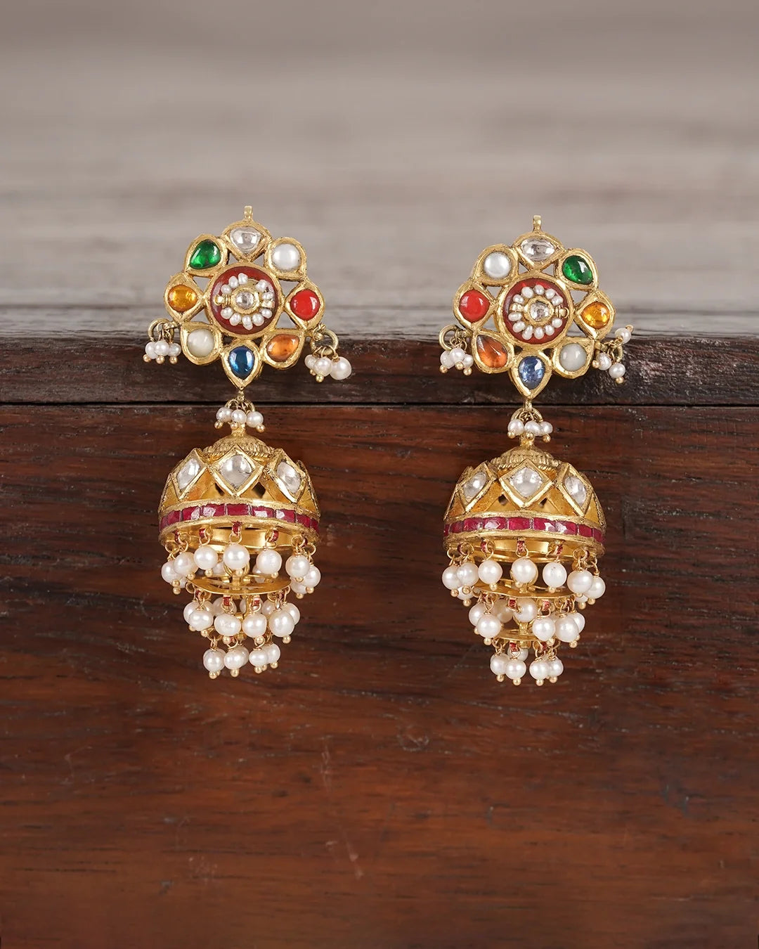 Gold domed jhumka earrings with Navratna gemstones, uncut polki diamonds, red enamel detailing, and cultured pearl fringes
