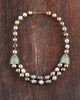 Sanea Necklace featuring multiple strands of cultured pearls with green enamel and rose-cut diamond disks, finished with diamond and emerald clasps