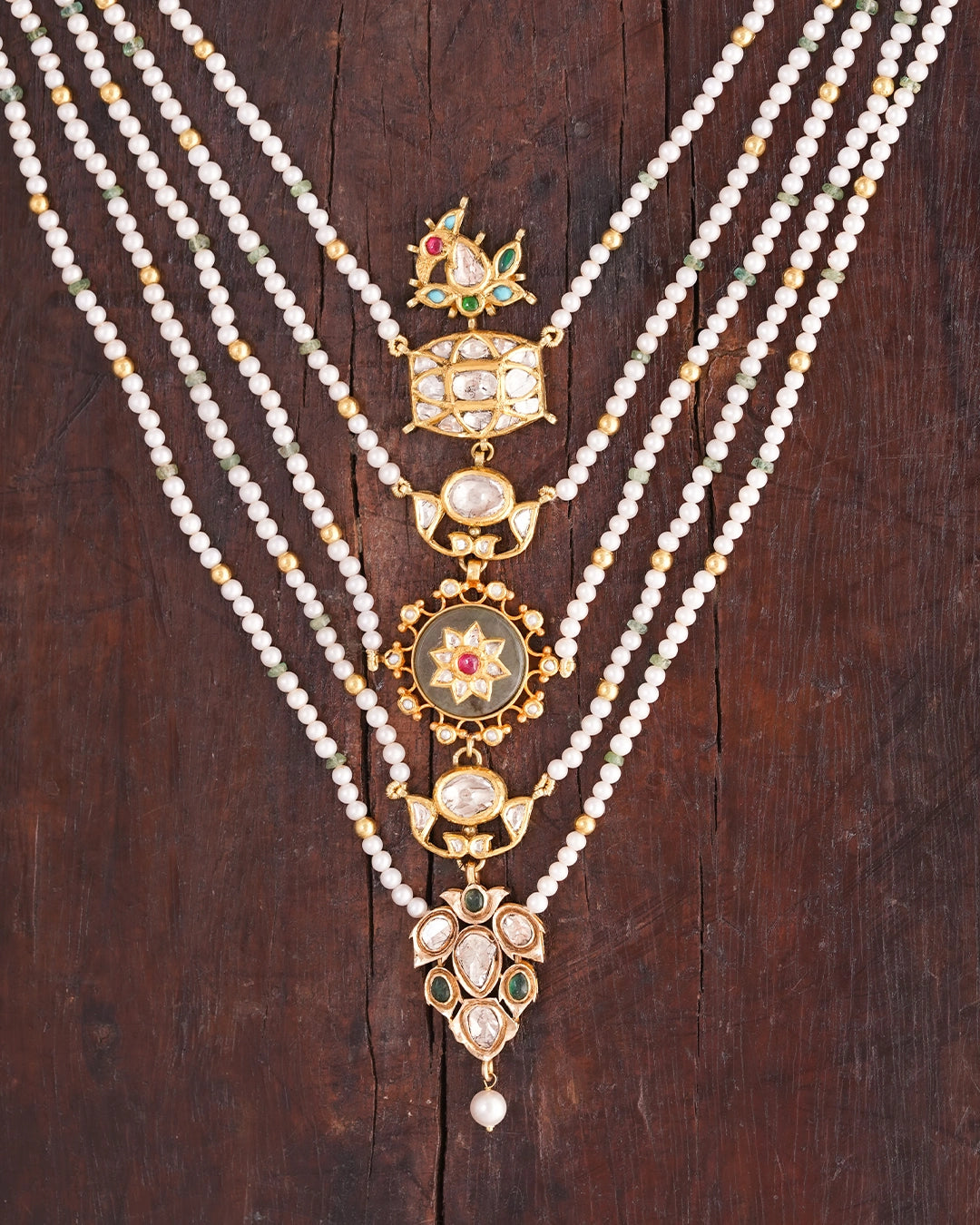 Layered panchlada necklace with pearls, emerald beads, uncut diamonds, and vibrant gemstones set in gold for women.