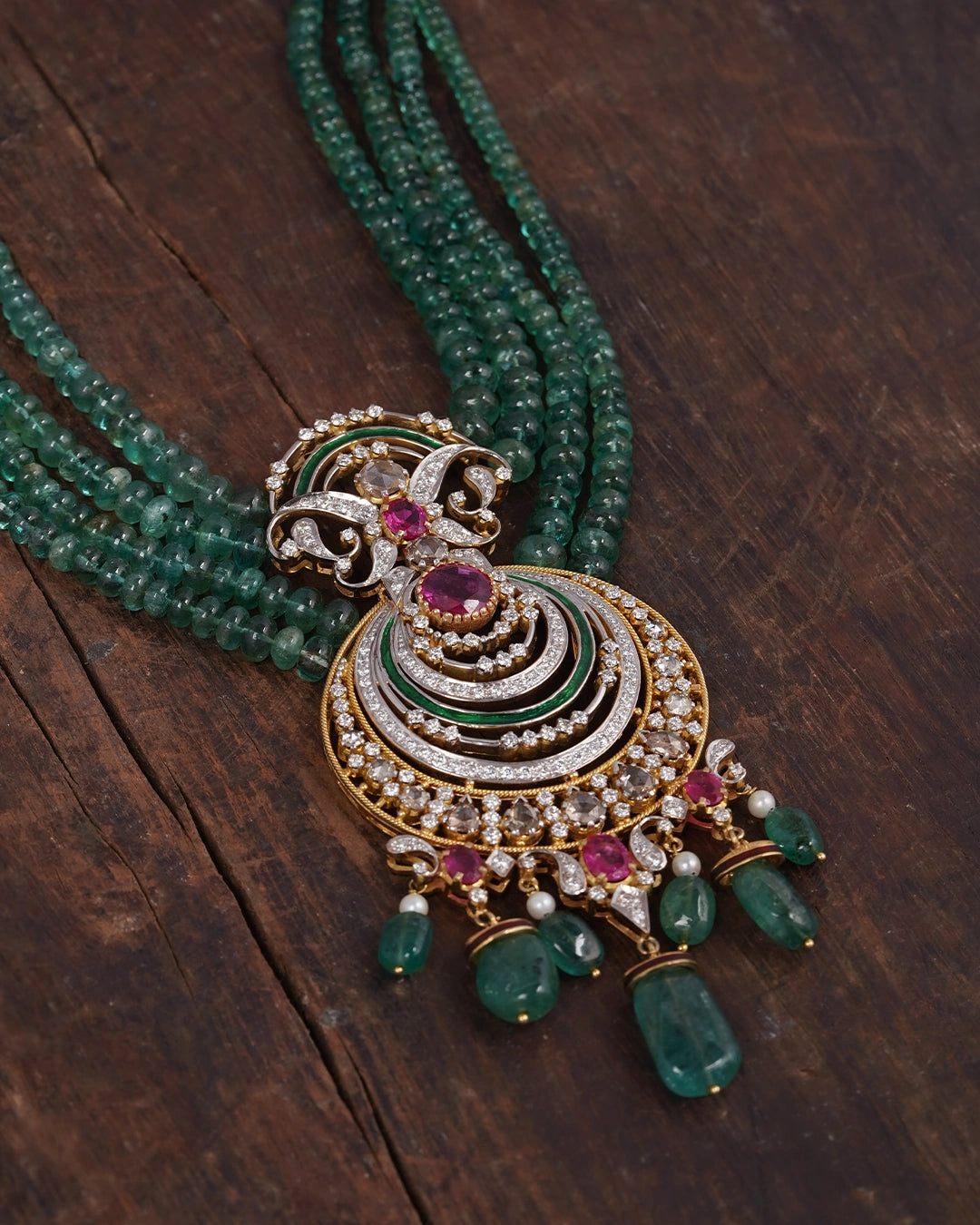 Zyar Necklace in gold featuring a crescent pendant set with natural brilliant-cut diamonds, a glass-filled ruby, and green enamel detailing, suspended from multi-strand emerald beads with emerald drops and cultured pearl finishes.